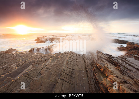 Brechenden Wellen bei Sonnenuntergang an einem steinigen Strand in Big Sur, Kalifornien Stockfoto