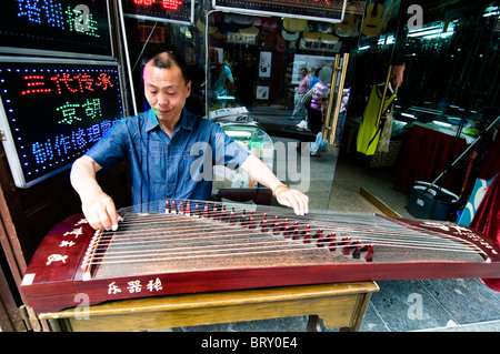 Ein chinesischer Mann Guzheng, ein traditionelles Musikinstrument zu spielen. Stockfoto