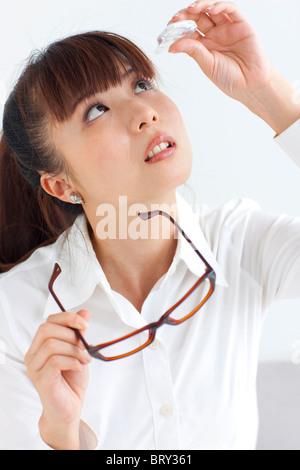 Junge Frau Anwendung von Augentropfen, weißer Hintergrund Stockfoto