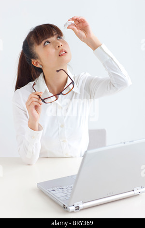 Junge Frau Anwendung von Augentropfen, weißer Hintergrund Stockfoto