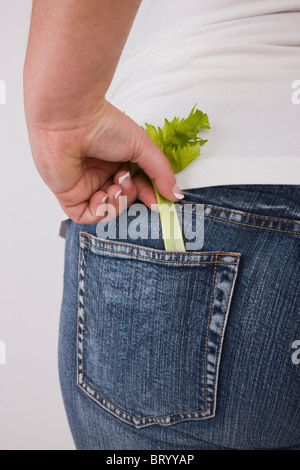 Übergewichtige Frau mit Sellerie in hinteren Jeans Tasche, Mittelteil, Rückansicht Stockfoto