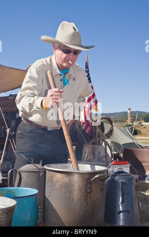 Zigarre rauchende Cowboy weckt den Pott, der Lincoln County Cowboy Symposium und Chuck Wagon Kochwettbewerb, Ruidoso Downs, New Mexico. Stockfoto