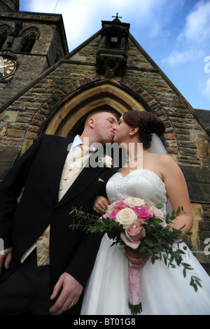 Braut und Bräutigam just married küssen außerhalb der Kirche Stockfoto