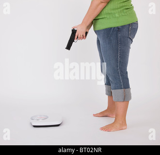 Übergewichtige Frau mit Pistole an Gewicht Waage, niedrige Abschnitt Stockfoto