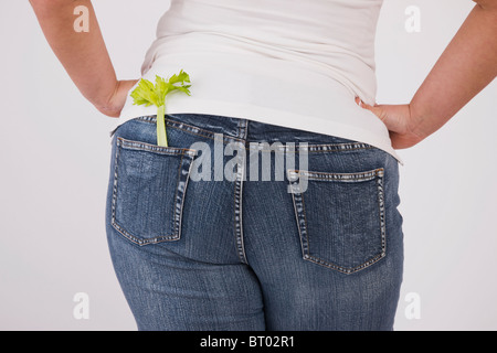 Übergewichtige Frau mit Sellerie in hinteren Jeans Tasche, Mittelteil, Rückansicht Stockfoto