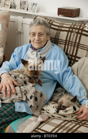 ältere Frau hält im Winter warm eingepackt mit Teppichen mit ihrem Haustier Hunde Stockfoto