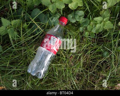 Coca Cola Plastikflasche auf Grünstreifen am Straßenrand verworfen Stockfoto
