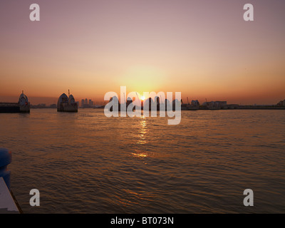 Die Themse Flut Barriere, ein Londoner Wahrzeichen bei Sonnenuntergang mit Canary Wharf im Hintergrund Stockfoto