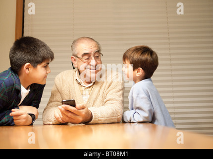 Großvater und Enkel mit Handy am Tisch Stockfoto