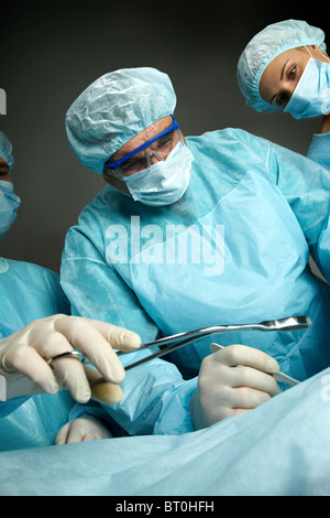 Seitenansicht der drei Chirurgen in Betrieb Stockfoto