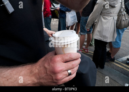 Die Hand eines Mannes geschmückt mit einem Ehering hält eine Take-away Tasse Kaffee mit einem Deckel außerhalb Borough Market, London England UK Stockfoto