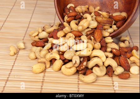 Eine verschüttete Holzschale gemischte Nüsse, wie Walnüsse, Haselnüsse, Mandeln und Cashew-Kerne. Stockfoto