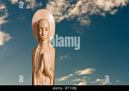 religiöse Figur geschnitzt auf einem Elfenbein Fang mit Himmel als Hintergrund Stockfoto