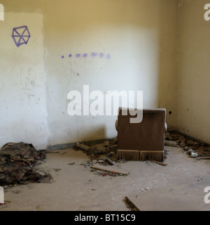 Sessel, Gesicht zur Wand in verlassenen Haus. Drogenkonsum Utensilien auf dem Boden. Stockfoto