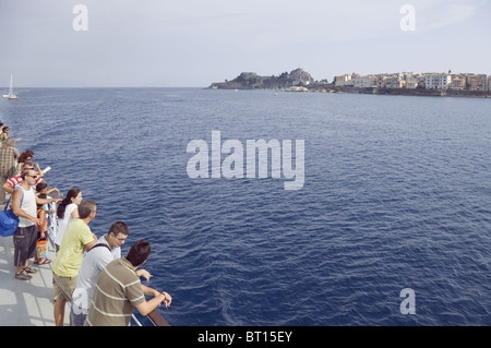 Insel Korfu, Griechenland, Europa. Die Passagiere an Deck der Fähre, da es Ansätze der Stadt Korfu in der Ferne sichtbar Stockfoto