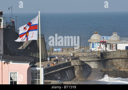 Die landwärtige Ende des Cromer Pier mit der Flagge der RNLI gesehen fliegen über die Küstenfischerei Rettungsboot-Haus Stockfoto