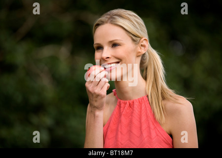 Eine Frau, die einen Apfel, im Freien zu essen Stockfoto