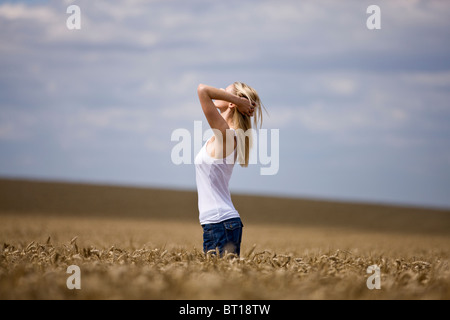 Eine Frau, die in ein Weizenfeld, Arme hinter dem Kopf Stockfoto