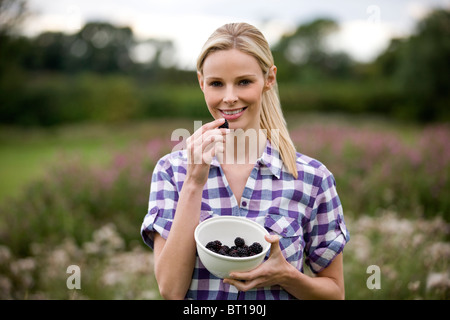 Eine Frau Essen frisch gepflückt Brombeeren, im freien Stockfoto