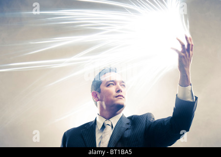 Licht strahlt aus japanischer Geschäftsmann Hände Stockfoto