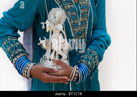 Indische Mädchen hält eine Silber Krishna statue Stockfoto
