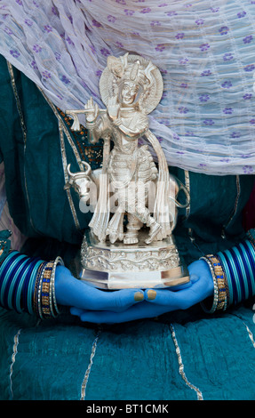 Indische Mädchen, dass eine Silber Krishna Statue mit blauen Händen. Indien Stockfoto