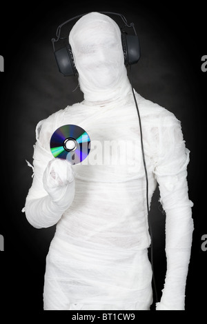 Mann im Verband mit Kopfhörer und CD auf schwarz Stockfoto
