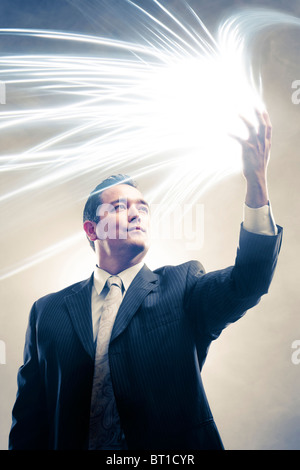 Licht strahlt aus japanischer Geschäftsmann Hände Stockfoto