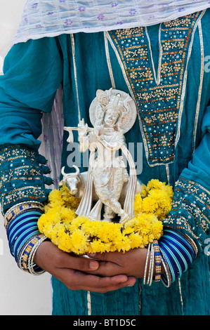 Indische Mädchen hält eine Silber Krishna statue Stockfoto