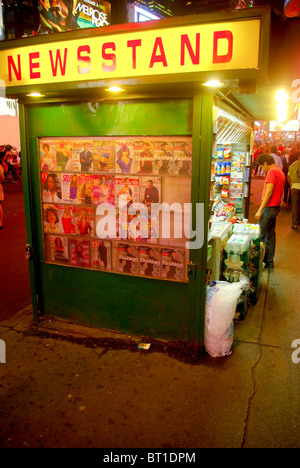 Mann einen Kiosk nahe 42nd Street in Manhattan in der Nacht Surfen. Zeitschriften angezeigt unter Windows der Kiosk in New York City. Stockfoto