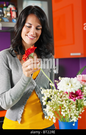 Mitte Erwachsene Frau Gerbera in blauen Topf setzen. Vertikale Form, Vorderansicht, Hüfte aufwärts Stockfoto