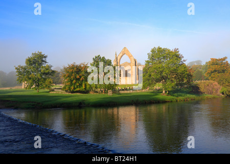 Bolton Priory und Stepping Stones River Wharfe im Herbst Nebel, Bolton Abbey, Yorkshire Dales National Park, North Yorkshire, England, UK. Stockfoto