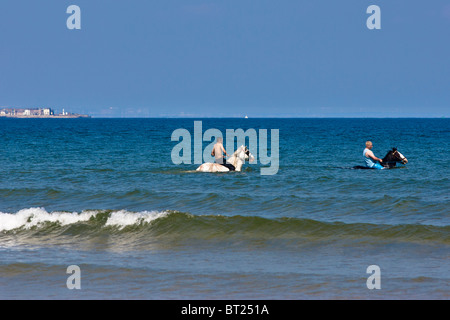 Zwei Pferde und ihre Reiter Kopf bis zur Nordsee in Redcar, abkühlen lassen, da die Temperaturen steigen. Stockfoto