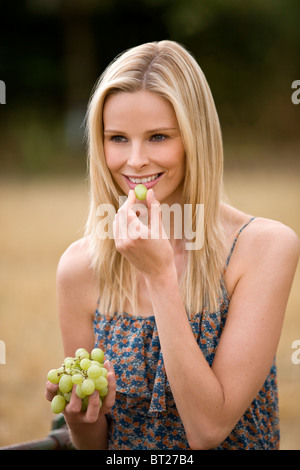 Eine Frau, die Trauben, im Freien zu essen Stockfoto