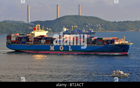 Container-Schiffe transportieren Fracht in Hong Kong vom Festland China bei Sonnenuntergang, Victoria Harbour, Hong Kong, China. Stockfoto