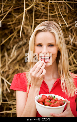 Eine Frau, eine Schale mit Erdbeeren, im Freien zu essen Stockfoto