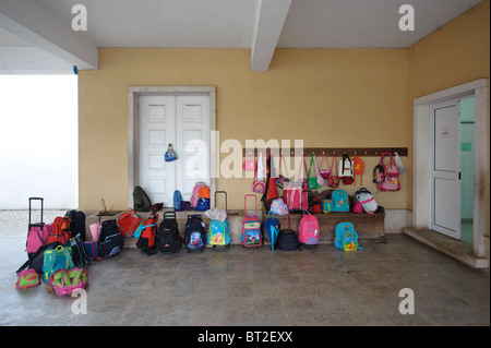 Kinder Taschen und Rucksäcke an Haken hängen und liegen auf dem Boden außerhalb einer Klasse in einer Grundschule Stockfoto