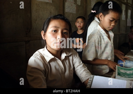 Eine Studentin sitzt an ihrem Schreibtisch am Ende des Schultages an The Ban Buamlao Primary School in Ban Buamlao, Laos, Stockfoto