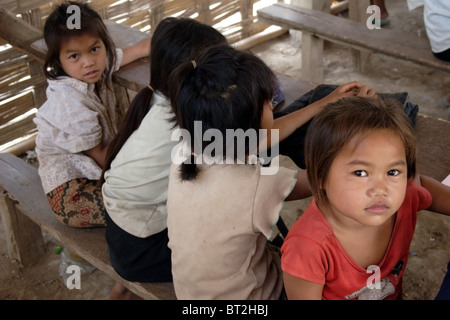 5 bis 7 jährige Mädchen sitzen während des Unterrichts an der Ban Buamlao Primary School in Ban Buamlao, Laos an Holztischen. Stockfoto