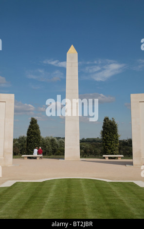 Besucher sitzen in der Nähe der steinernen Nadel im Armed Forces Memorial, National Memorial Arboretum, Alrewas, Staffordshire, UK. Stockfoto