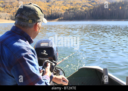 Ältere Mann Angeln und trolling von Rückseite kleine Aluminium-Boot oder Skiff. Hochgebirgssee im Herbst. Stockfoto
