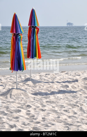 Verlassenen Strand mit geschlossenen Schirmen. Off Shore Bohrinsel im Hintergrund. Stockfoto