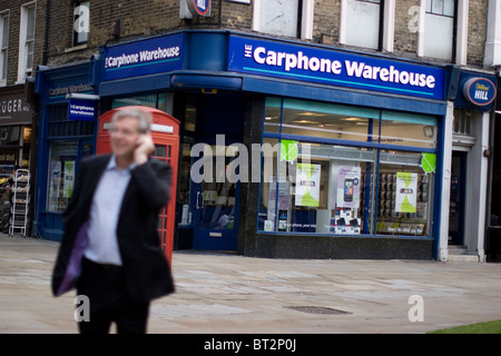 Carphone Warehouse Handy Outlet Ladengeschäft, Mitglied der Öffentlichkeit am Telefon vor roten Telefonzelle Stockfoto