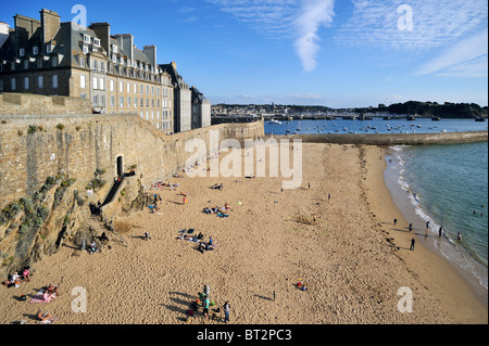 Touristen, Sonnenbaden am Strand vor dem Wall in Saint-Malo, Bretagne, Frankreich Stockfoto