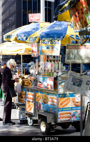 Eine Frau kauft einen Hot Dog von einem Straßenhändler auf der Straße in Downtown Manhattan Stockfoto