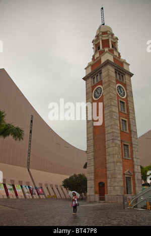 Befindet sich am südlichen Ufer von Tsim Sha Tsui, ist der Clock Tower eines der ältesten Wahrzeichen Hongkongs. Dame mit Schirm Stockfoto