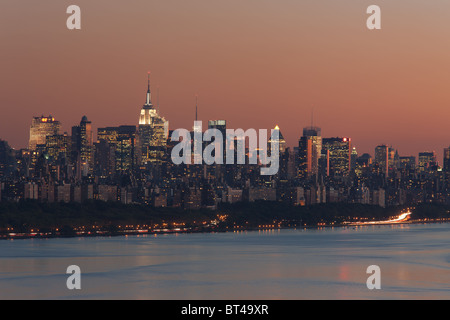 Der Himmel leuchtet Orange über die Skyline von Manhattan und den Hudson Fluss kurz nach Sonnenuntergang in New York City. Stockfoto