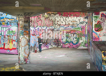 Ein Teenager malt Graffiti in der Skateboard Haven unter Queen Elizabeth Hall auf der South Bank in London, Vereinigtes Königreich. Stockfoto