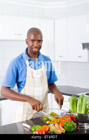 junge afrikanische amerikanische glücklich machen einen gesunden Salat in Küche Stockfoto