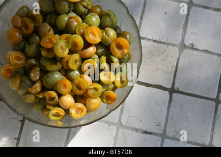 (Prunus X domestica var. Syriaca) Halbierten und entsteinten Mirabellen in eine Glasschüssel. Stockfoto